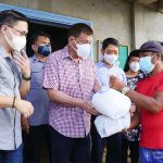 President Rodrigo Roa Duterte, assisted by Senator Christopher Lawrence Go, hands over a relief pack to one of the victims of Typhoon Odette in San Jose, Dinagat Islands on December 22, 2021. JOEY DALUMPINES/ PRESIDENTIAL PHOTO