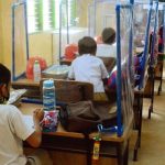 Grade 1 pupils sit on chairs with desks installed with plastic barriers while attending class at the La Huerta Elementary School in Parañaque City on Monday (Dec. 6, 2021). Some 28 public schools in Metro Manila joined the pilot run of face-to-face classes in the region. (PNA photo by Avito Dalan)