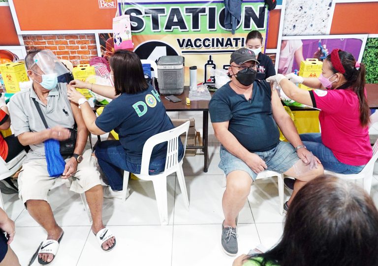 Health workers administer a Pfizer Covid-19 booster shot to two elderly men at the vaccination area of a mall along Quirino Highway, Caloocan City [PNA photo | Ben Briones]