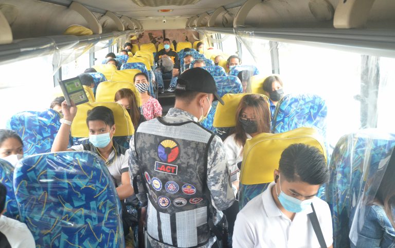 An officer of the Inter-Agency Council for Traffic (I-ACT) checks the vaccination cards of passengers of a public utility bus in compliance with the "no vaccination, no ride" policy along Mindanao Avenue, Quezon City on Thursday (Jan. 20, 2022). (PNA photo by Robert Oswald Alfiler)