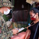 A COVID-19 checkpoint where a local civilian is having her vaccination card checked. (Photo from PNA)