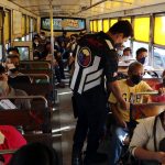 A member of the Inter-Agency Council for Traffic (IACT) checks the vaccination cards of the passengers inside a bus along Commonwealth Avenue in Quezon City on Monday (Jan. 24, 2022). (PNA photo by Joey O. Razon)